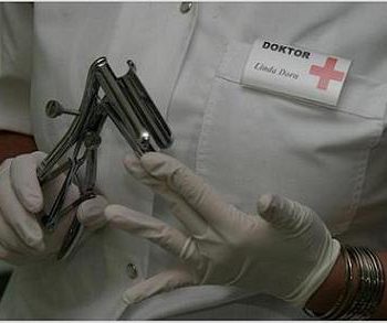 Oberkörper von Doktor Linda Dorn im weißen Kittel und weißen Handschuhen hält ein Metall Gerät für anale Untersuchung in der Hand haltend