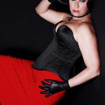 Domina Linda Dorn stehend im engen schwarzem Korsett und engem rotem Kleid in Pose